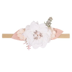 Detailed shot of large white fabric flower baby headband with pearls and rhinestones