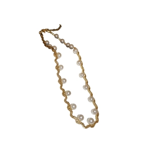 French vintage wavy gold necklace with elegant imitation pearls on a white background