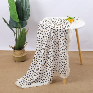 Detailed view of leopard print cotton muslin baby blanket with white tassel edges