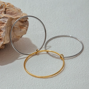 Close-up of minimalist gold and silver stainless steel bangles on natural stone