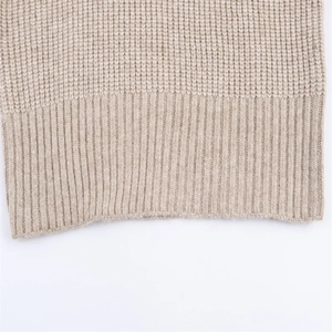 Détail macro de la maille gaufrée beige et de l'ourlet côtelé sur un pull à manches longues