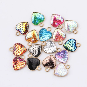 Flat lay of colorful heart-shaped fish scale pendants with metallic frames for DIY jewelry