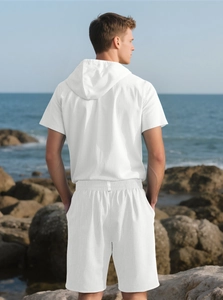Rear view of men white linen hooded t-shirt and shorts set on a scenic coastal rock