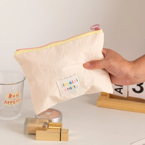 Close-up of cream fabric makeup bag with contrast zippers and jimeizi pretty logo patch