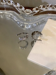 Vue macro de boucles d'oreilles serpent en argent avec zircons sur une surface miroir