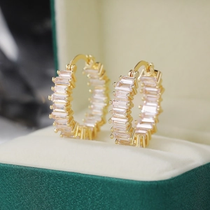 Macro shot of gold hoop earrings with row of emerald-cut cubic zirconia in a velvet box