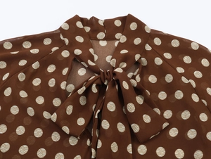 Détail du chemisier en mousseline marron à pois avec nœud papillon élégant au col