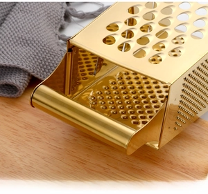 Close-up of golden stainless steel grater with ergonomic handle on wooden board