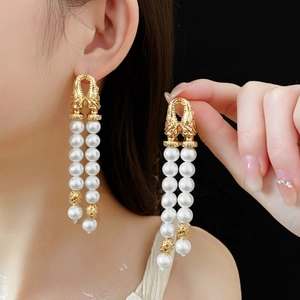 Detail of vintage gold earrings with double-row faux pearl tassels and ornate carvings
