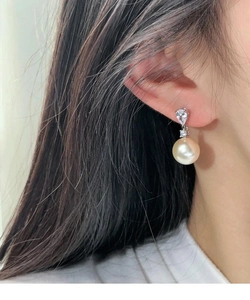 Gros plan d'une boucle d'oreille en perle et zircon en argent portée par un mannequin