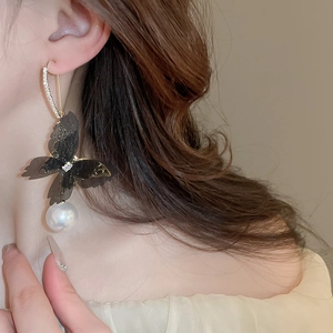 Detail of mesh butterfly earrings with sparkling rhinestones and white hanging pearl