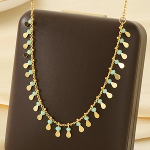 Detail of gold collar necklace with turquoise beads and golden teardrop pendants