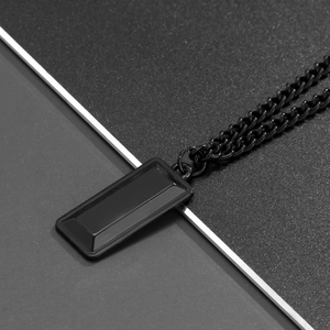 Close-up of a black geometric rectangular pendant on a matching Cuban link chain
