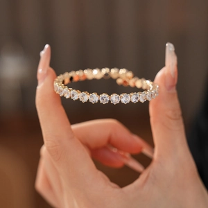 Detailed close-up of a sparkling gold-plated tennis bracelet with round white zircons