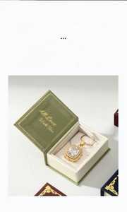 Close-up of a square gold pendant necklace with crystals inside a green velvet box