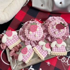 Pink strawberry hair clip and scrunchie set featuring plaid patterns and plush charms