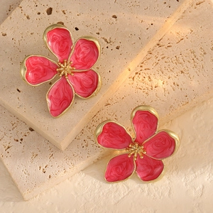 Macro detail of peach pink enamel flower earrings with golden stamens on stone