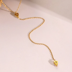 Detail of a golden Y-shaped tassel necklace with clear drop-shaped crystal pendants