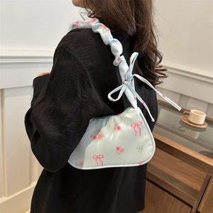 Light blue floral shoulder bag with pink roses and ruffled strap worn by a model