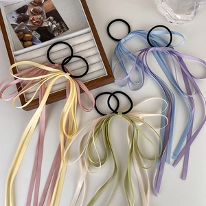 Flat lay of colorful satin ribbon bow hair ties in assorted pastel colors on a soft surface