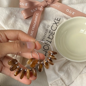 Detail of vintage resin hoop earrings featuring amber beads held by hand