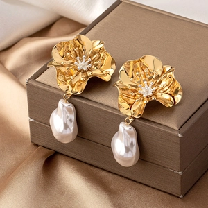 Macro shot of gold flower earrings with baroque pearls and diamond accents on silk
