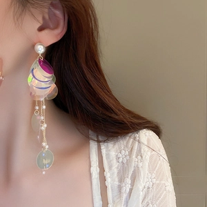 Close-up of model wearing long laser sequin tassel earrings with white pearls