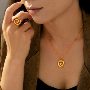 Elegant gold spiral jewelry set featuring a necklace and ring on a professional model