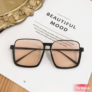 Macro detail of retro square sunglasses with black frame and champagne lenses on a desk