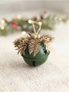 Close-up of green and gold Christmas bell ornament with pine needles and twine string