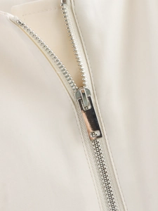 Nahaufnahme des silbernen Metallreißverschlusses auf cremefarbenem Westentextil