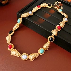 Detail of vintage gold necklace with red black and turquoise stones on leather background