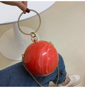 Detailed close-up of a red marble acrylic spherical handbag with rhinestone ring handle