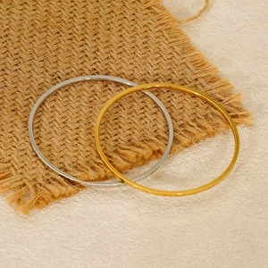 Polished gold and silver stainless steel minimalist bangles on a linen background