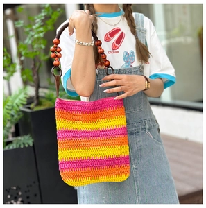Detail of colorful rainbow straw bucket bag with unique wooden bead woven handles