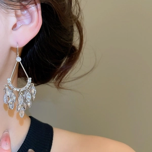 Macro detail of teardrop tassel earrings with sparkling zircons worn by a model