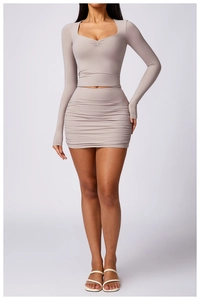 Detail of taupe two-piece set featuring pleated mini skirt and long sleeve crop top