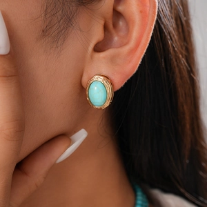 Detailed close-up of retro bohemian oval turquoise stud earrings with golden relief frame