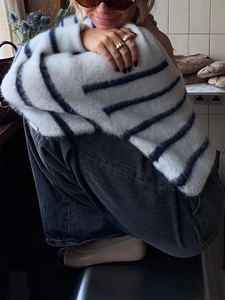 Detail of soft striped knit sweater texture and relaxed fit on a seated model