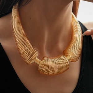 Detail of chunky gold coiled spring necklace showing bold metallic texture on a model