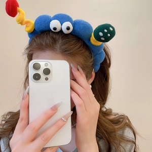 Nahaufnahme eines blauen Plüsch-Cartoon-Stirnbands mit großen Augen und bunten Bändern