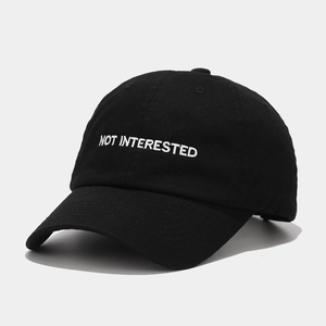 Detailed view of black cotton baseball cap with white NOT INTERESTED embroidery
