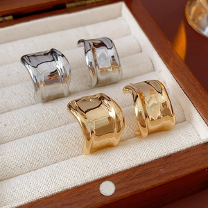 Makroaufnahme von gold- und silberfarbenen Wellen-Ohrringen in einer Holz-Schmuckbox