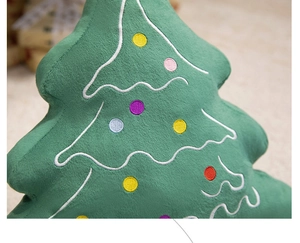 Detail view of green plush Christmas tree pillow with colorful embroidery and soft texture