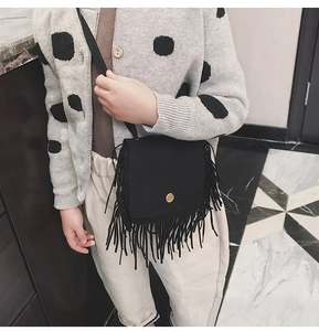 Close-up of a black fringe crossbody bag for girls with soft suede texture and gold buckle