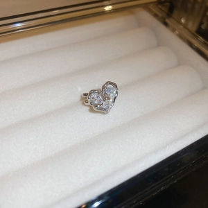 Close-up of a silver heart-shaped ear cuff with sparkling zircons in a jewelry box