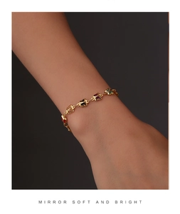 Detail of gold-plated bracelet featuring colorful butterfly charms on a slender chain