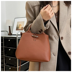 Close-up of caramel lychee grain leather handbag with iconic metallic bamboo toggle clasp