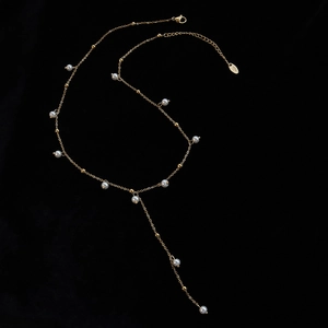 Elegant 18k gold plated Y-shaped necklace with delicate pearls on a sleek black background