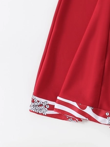 Detail view of red tankini swim dress hem with black and white skull printed trim
